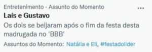 A screenshot of a news item about Lais and Gustavo, found in the “Entertainment – Trending Topics” section, with the headline: “The two shared a kiss after the party ended early this morning on ‘BBB’.” The image also displays related topics: “Natália and Eli” and “#leaderparty” (#festadolíder).